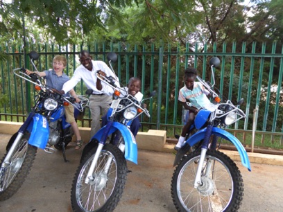 The three kids try out the Riders for Health motorcycles that Gordon is about tot ride across Zambia